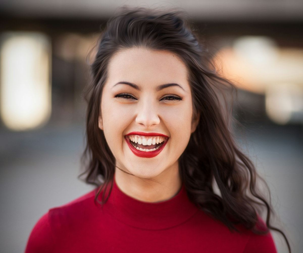 A woman laughing with a bright, confident smile