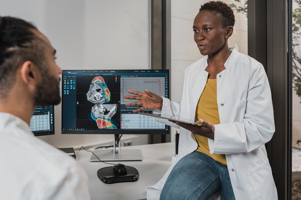 Two clinicians reviewing 3D dental scans on a monitor during implant planning